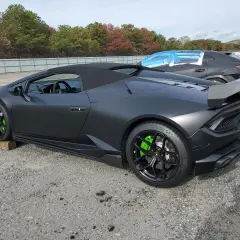 Matowy czarny lambo huracan z jaskrawozielonymi zaciskami hamulcowymi stoi na żwirowym placu.