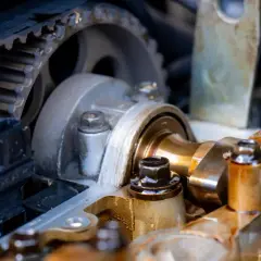 Widok mechanizmu rozrządu silnika samochodowego z paskiem zębatym i wałkami.