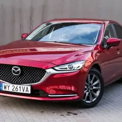 Czerwona Mazda 6 2.0 benzyna z polskimi tablicami rejestracyjnymi stoi na chodniku.