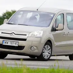 Beżowy Citroen Berlingo 1.6 HDI z polskimi tablicami WW 1874S jedzie po drodze wśród zieleni.