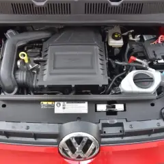 Silnik 1.0 TSI w czerwonym samochodzie Volkswagen. Widoczny akumulator, płyny i osłona silnika.