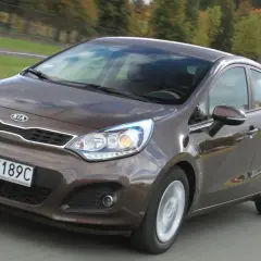 Brązowy Kia Rio w ruchu drogowym. Wiele osób szuka kia rio opinie, ten model jest dobrym wyborem.