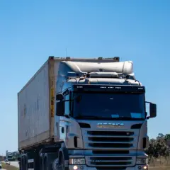 Ciężarówka Scania z kontenerem na autostradzie pod błękitnym niebem.