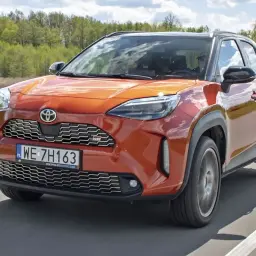 Pomarańczowy Toyota Yaris Cross GR Sport w ruchu. Wiele osób szuka **toyota yaris opinie** przed zakupem.
