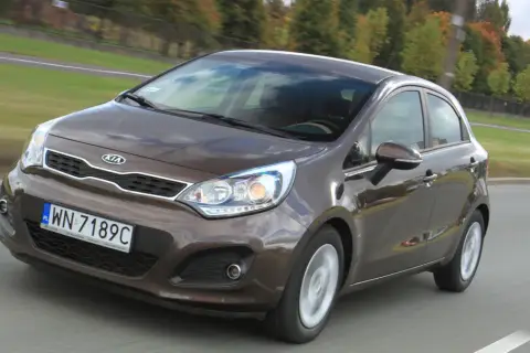 Brązowy Kia Rio w ruchu drogowym. Wiele osób szuka kia rio opinie, ten model jest dobrym wyborem.
