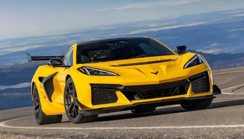 Żółty Chevrolet Corvette C7 ZR1 z dużym tylnym skrzydłem pędzi po górskiej drodze, gotowy na każde wyzwanie.
