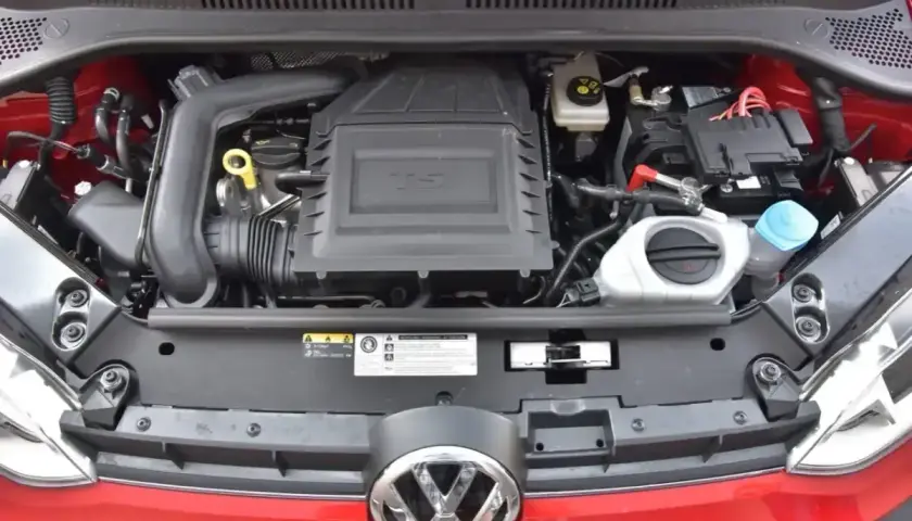 Silnik 1.0 TSI w czerwonym samochodzie Volkswagen. Widoczny akumulator, płyny i osłona silnika.