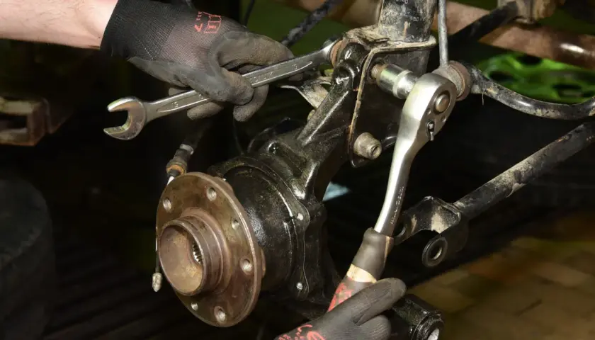 Mechanik dokręca śruby przy piaście, gdzie znajduje się łożysko w kole.