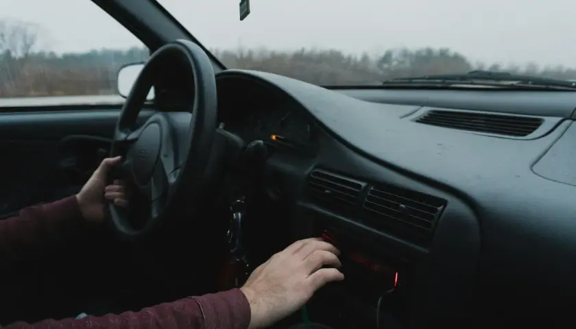 Ręka kierowcy szuka kodu do radia Renault, by włączyć ulubioną muzykę podczas podróży.