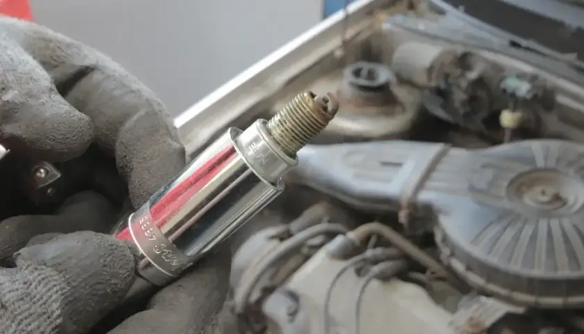 Rękawica trzyma świecę zapłonową, potencjalnie przyczynę błędu dtc p0300 renault.