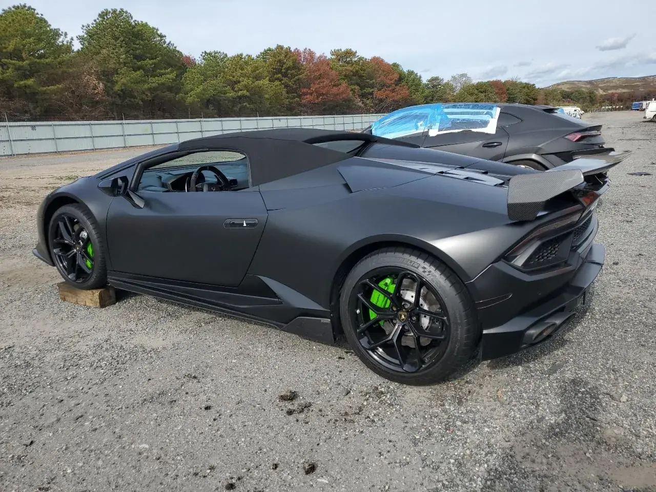 Matowy czarny lambo huracan z jaskrawozielonymi zaciskami hamulcowymi stoi na żwirowym placu.