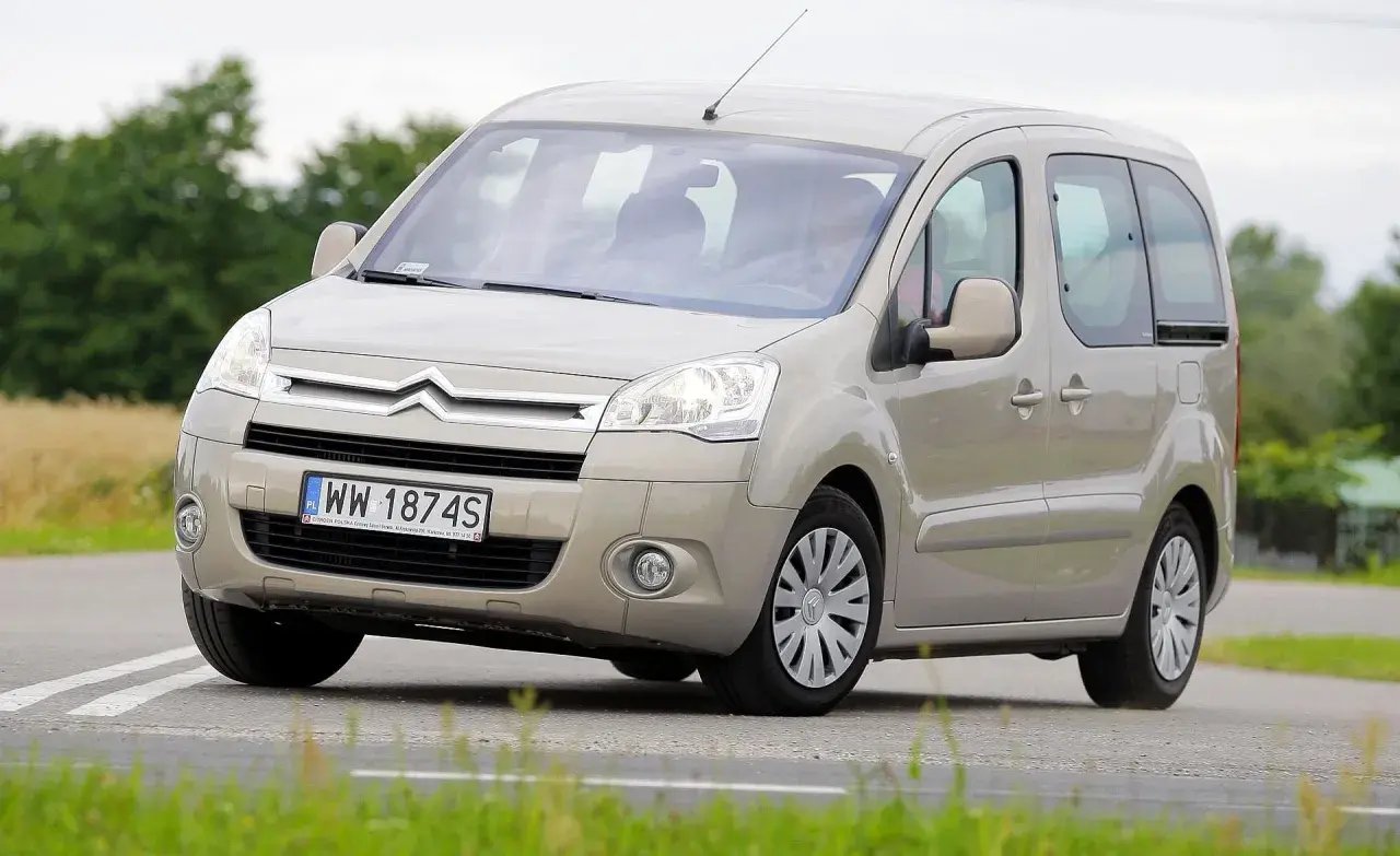 Beżowy Citroen Berlingo 1.6 HDI z polskimi tablicami WW 1874S jedzie po drodze wśród zieleni.