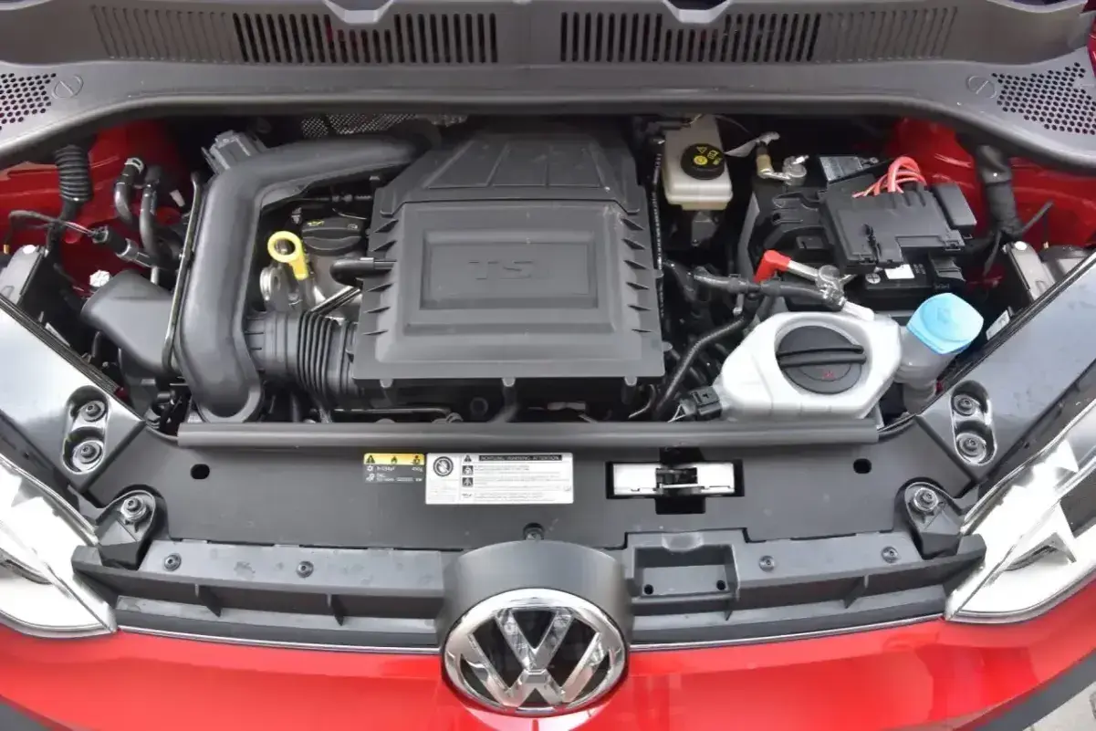Silnik 1.0 TSI w czerwonym samochodzie Volkswagen. Widoczny akumulator, płyny i osłona silnika.
