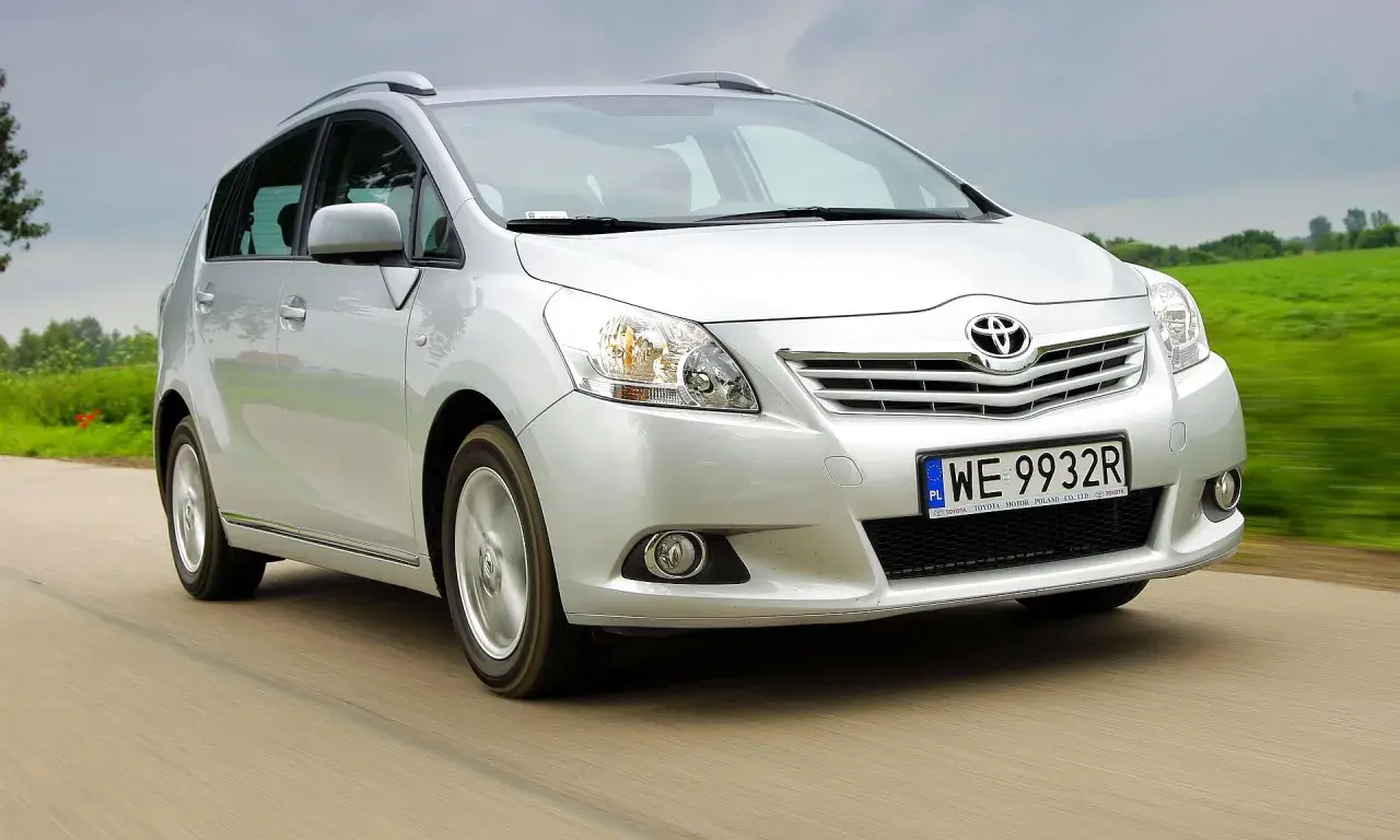 Srebrna Toyota Verso 1.8 benzyna w ruchu, z zielonym polem w tle.
