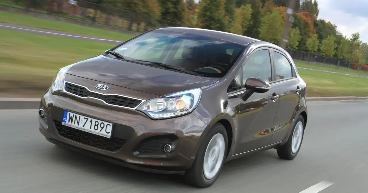 Brązowy Kia Rio w ruchu drogowym. Wiele osób szuka kia rio opinie, ten model jest dobrym wyborem.