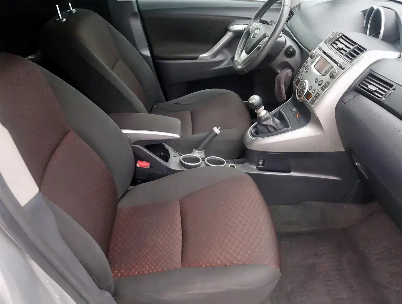 Wnętrze Toyoty Verso 1.8 benzyna. Widoczne fotele z tkaniny, dźwignia zmiany biegów i deska rozdzielcza.